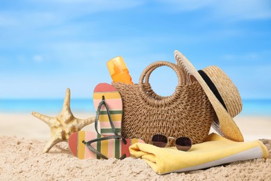 Image of Bag with sunscreen and accessories on sunny ocean beach. Summer vacation