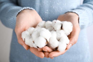 Young woman holding fluffy cotton flowers, closeup