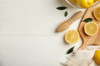 Photo of Citrus reamer and fresh lemons on white wooden table, flat lay. Space for text