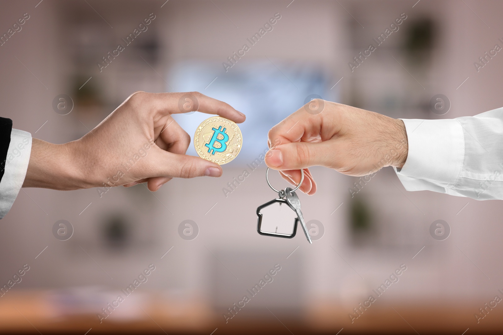 Image of Bitcoin exchange. Man using cryptocurrency to buy house. Seller holding key and buyer with bitcoin indoors, closeup