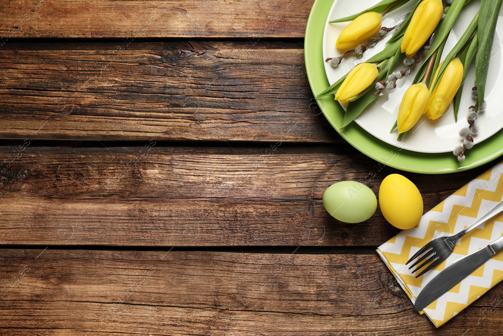 Photo of Festive Easter table setting with beautiful tulips and willow branches, flat lay. Space for text