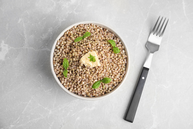 Photo of Tasty buckwheat porridge with butter on grey marble table, flat lay