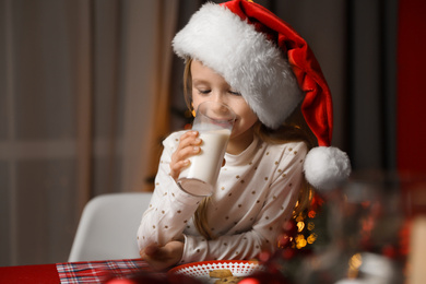 Cute little child drinking milk at table in dining room. Christmas time