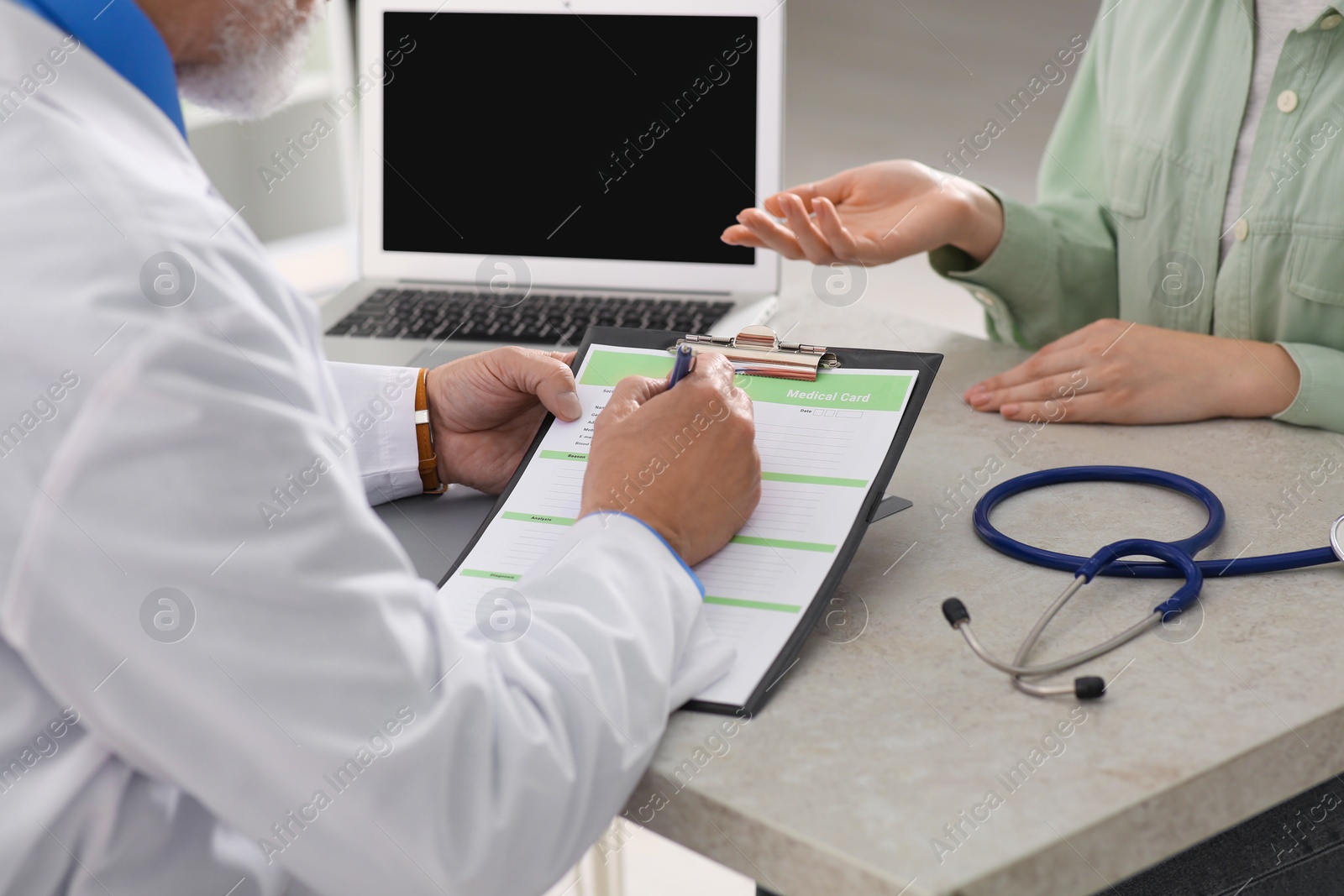 Photo of Doctor filling patient's medical card in clinic, closeup