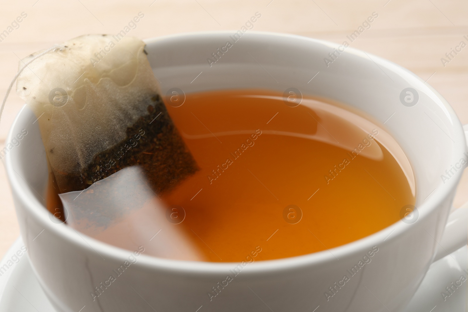 Photo of Tea bag in cup on table, closeup