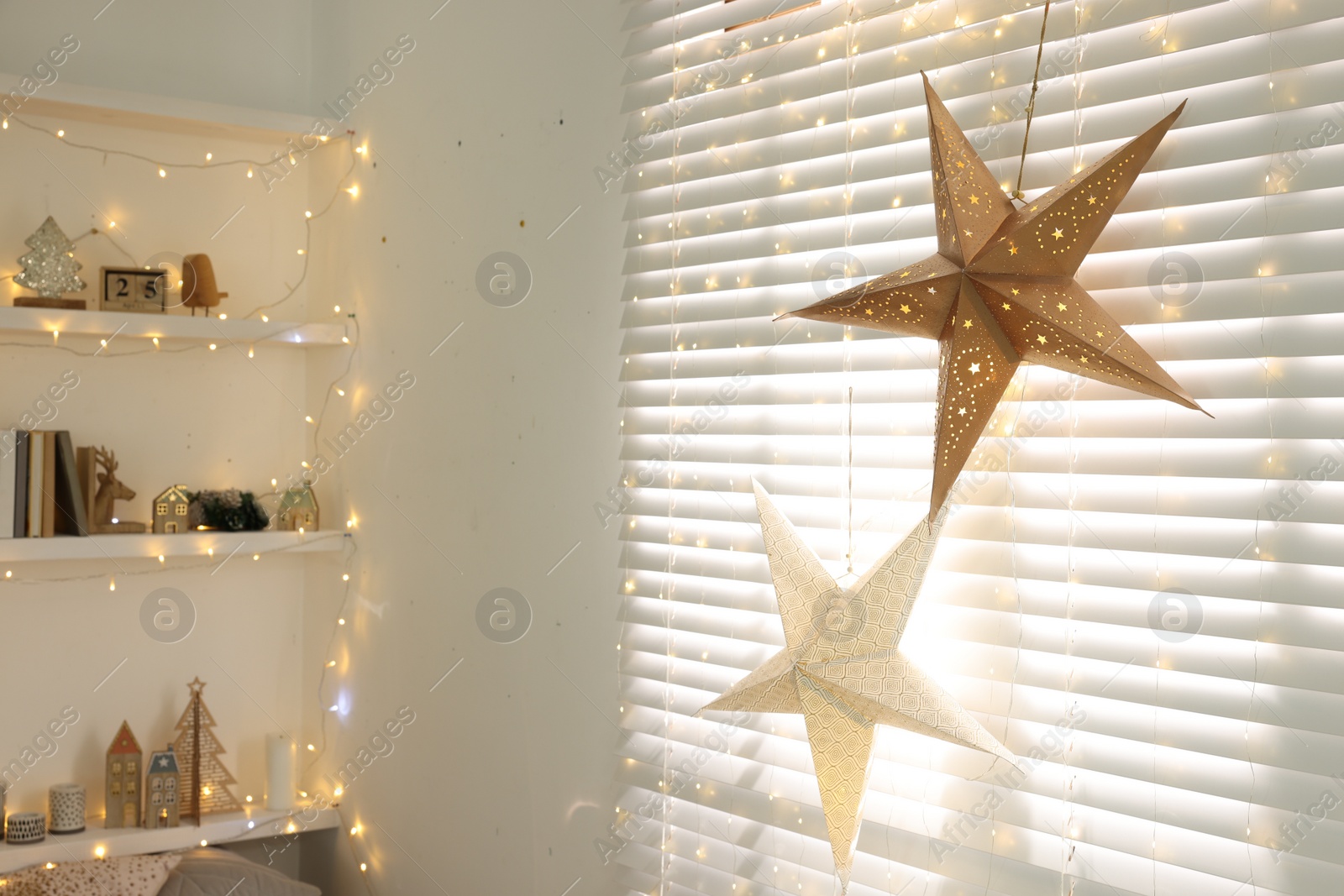 Photo of Beautiful decorative stars and festive lights in room. Christmas atmosphere