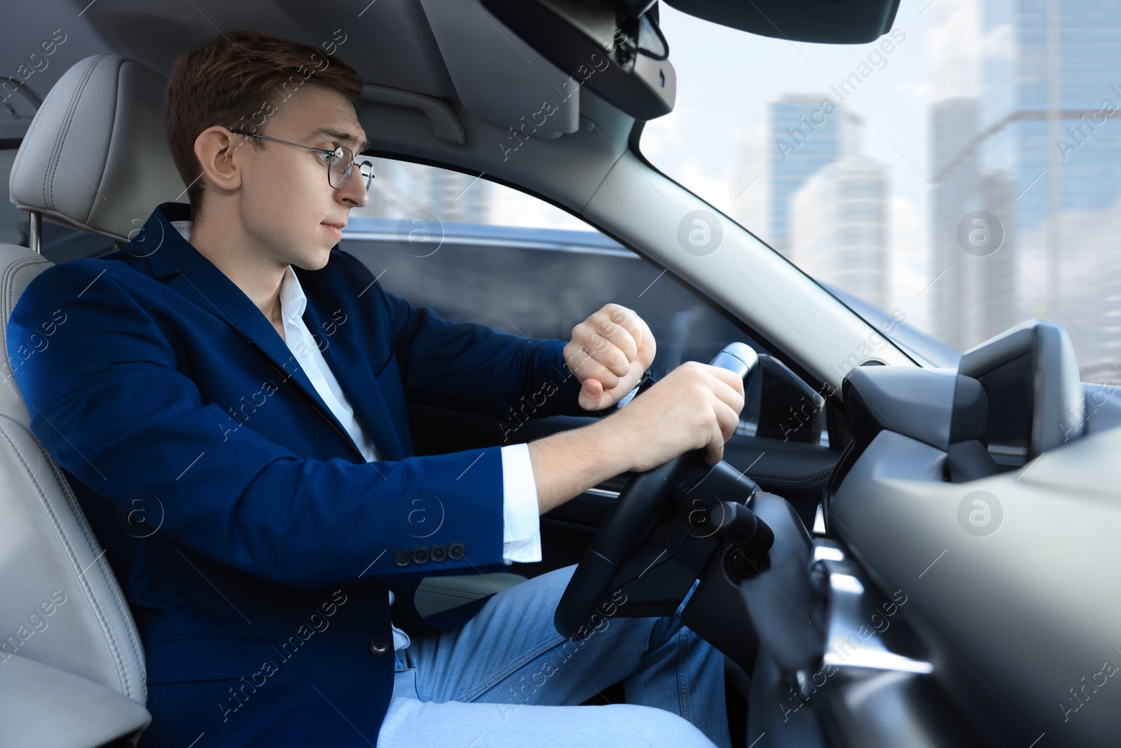 Photo of Young man checking time in car. Being late