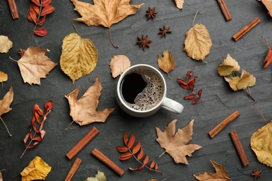 Photo of Flat lay composition with cup of hot drink and autumn leaves on black table. Cozy atmosphere