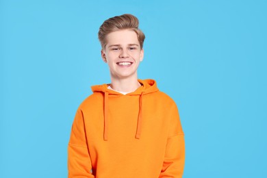 Portrait of smiling teenage boy on light blue background