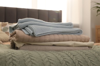 Photo of Stack of different folded blankets on bed in room. Home textile