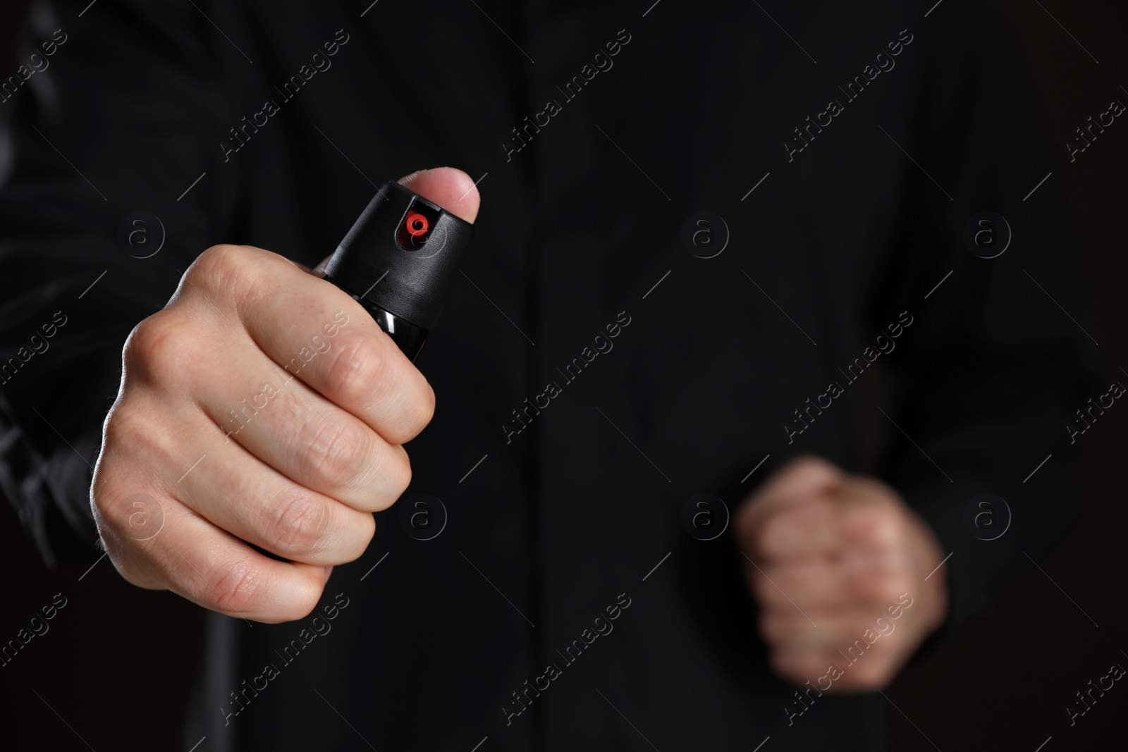 Photo of Man using pepper spray on black background, closeup. Space for text