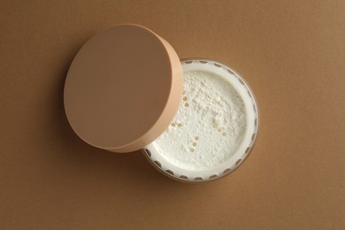 Photo of Rice loose face powder on brown background, top view. Makeup product