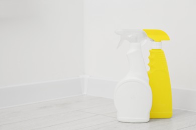Photo of Spray bottles of cleaning products indoors, space for text