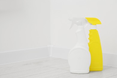 Spray bottles of cleaning products indoors, space for text