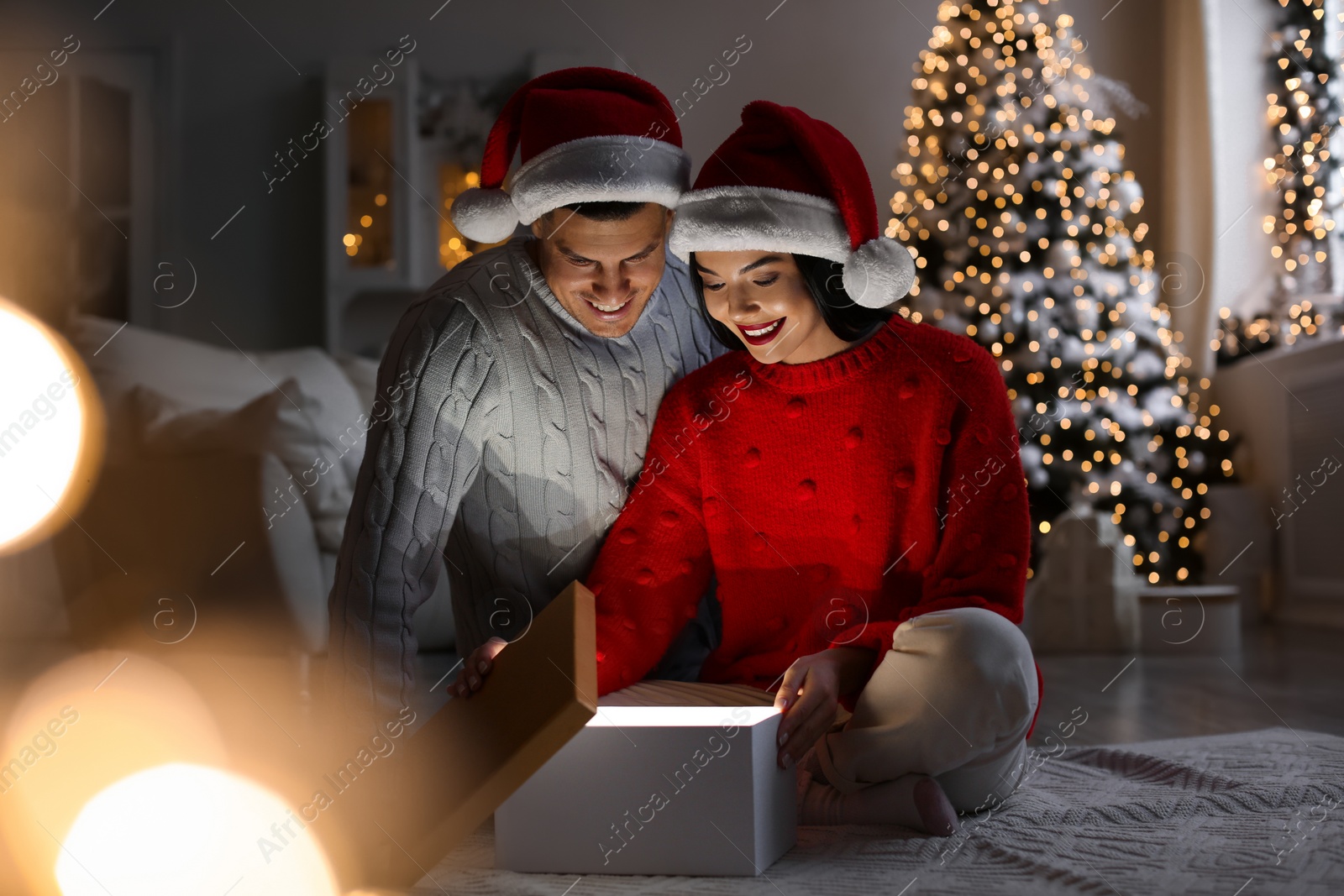 Photo of Happy couple opening magic gift box at home. Christmas celebration