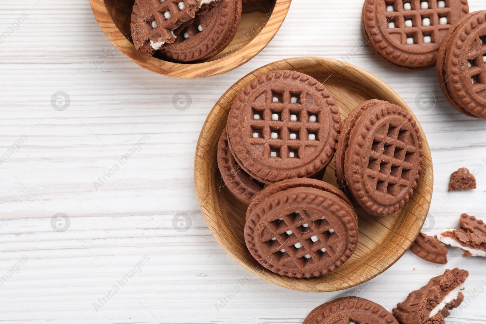 Photo of Tasty chocolate sandwich cookies with cream on white wooden table, flat lay. Space for text
