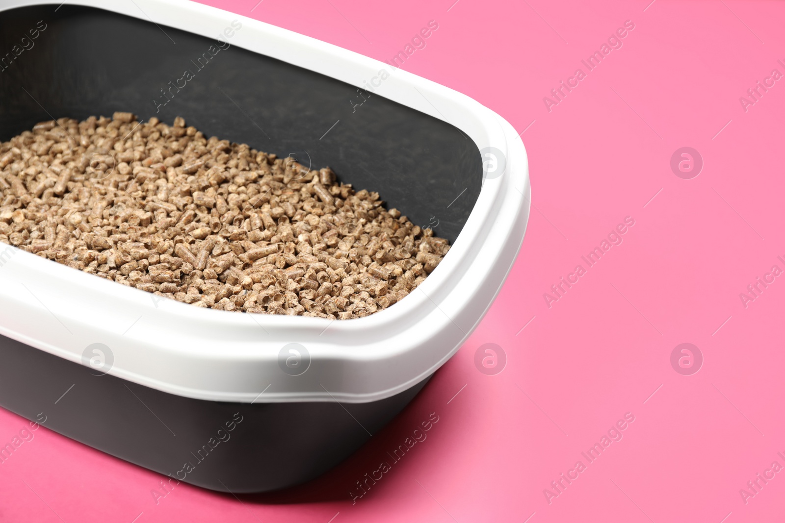 Photo of Cat litter tray with filler on pink background, closeup