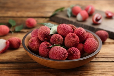 Photo of Fresh ripe lychee fruits in bowl on wooden table