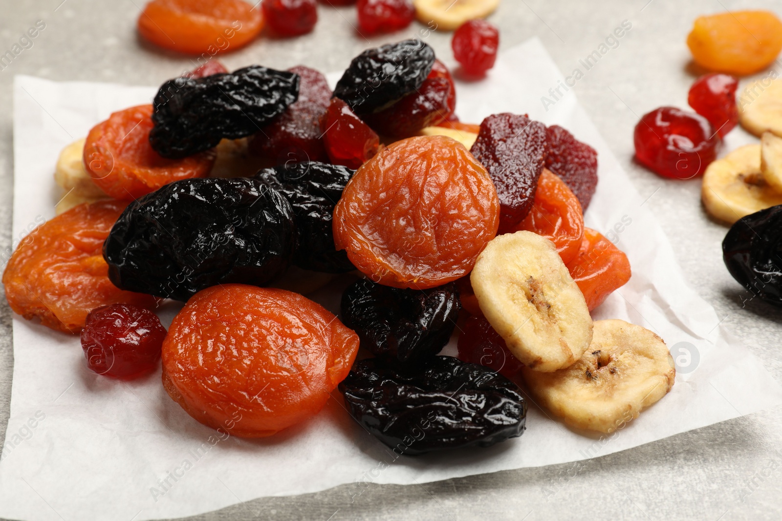 Photo of Mix of delicious dried fruits on grey table, closeup