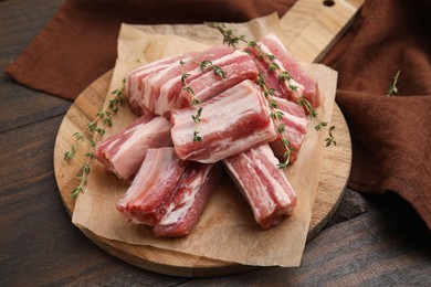 Photo of Cut raw pork ribs with thyme on wooden table