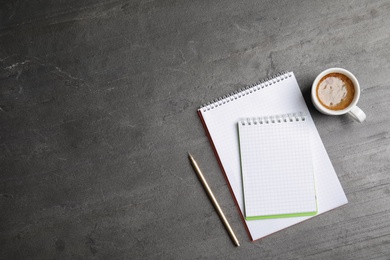 Notebooks and coffee on grey background, top view with space for text