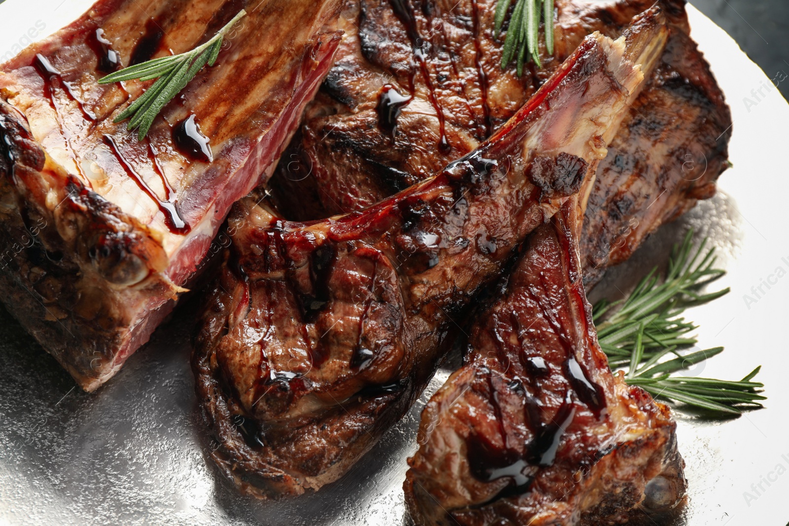 Photo of Delicious grilled ribs with rosemary in plate, closeup