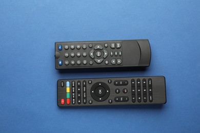 Different remote controls on blue background, flat lay