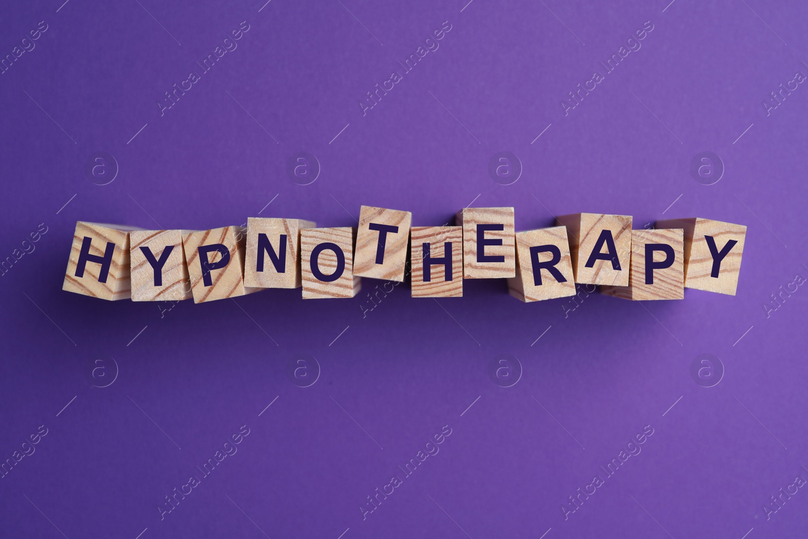 Photo of Wooden blocks with word HYPNOTHERAPY on purple background, flat lay