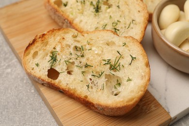 Tasty baguette with garlic and dill on light grey table, closeup