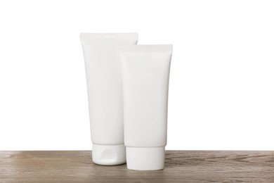 Photo of Tubes of hand cream on wooden table against white background