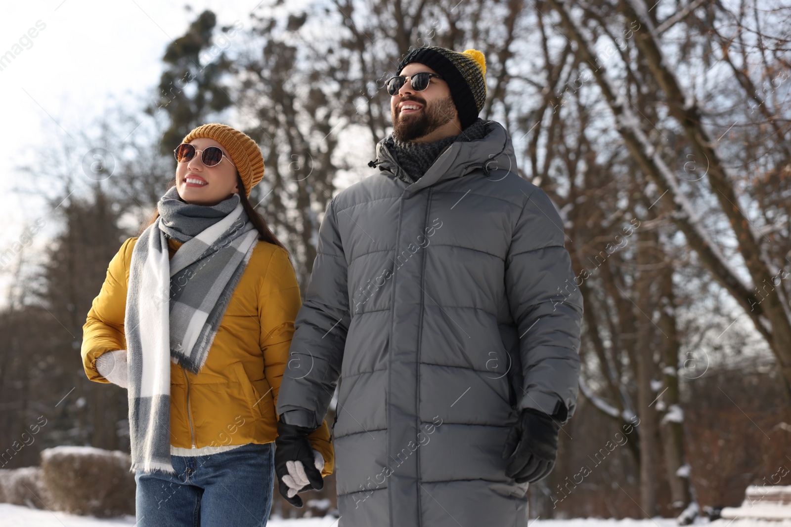 Photo of Beautiful happy couple walking in snowy park on winter day