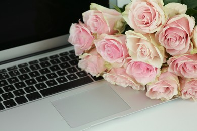Photo of Beautiful bouquet of roses near laptop on white table. Happy birthday greetings