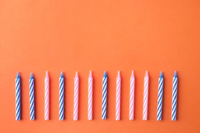 Photo of Colorful striped birthday candles on orange background, flat lay. Space for text
