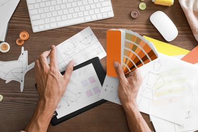 Photo of Male designer working at wooden table, top view