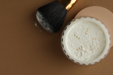 Photo of Rice loose face powder and makeup brush on brown background, flat lay. Space for text
