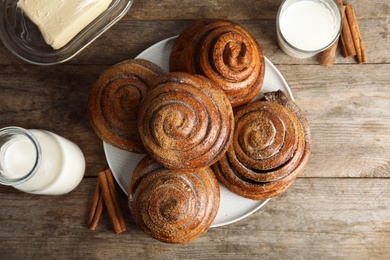 Flat lay composition with freshly baked cinnamon rolls on wooden background