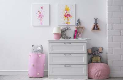 Photo of Chest of drawers and beautiful pictures in children's room. Interior design