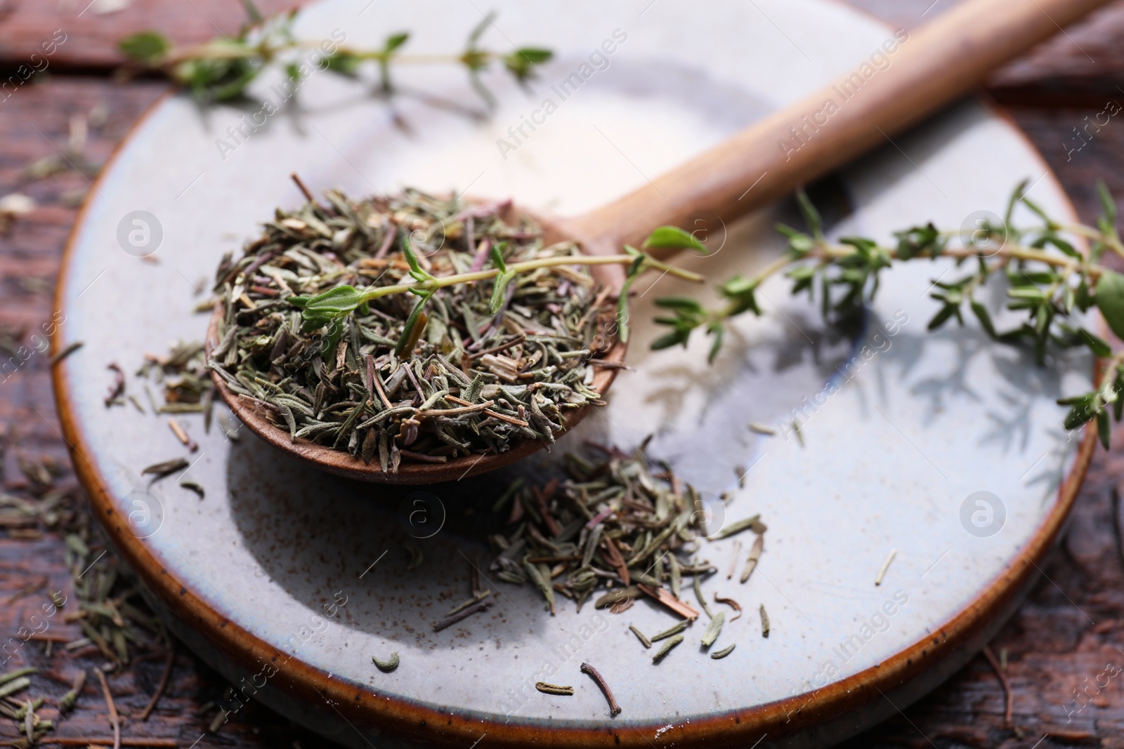 Photo of Spoon with dried thyme and fresh twigs on coaster, closeup