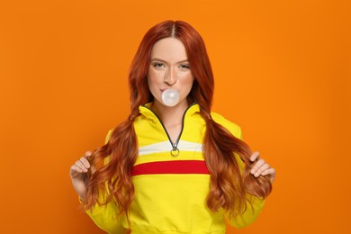 Photo of Portrait of beautiful woman blowing bubble gum on orange background