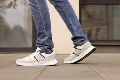 Photo of Man in jeans and sneakers walking on city street, closeup