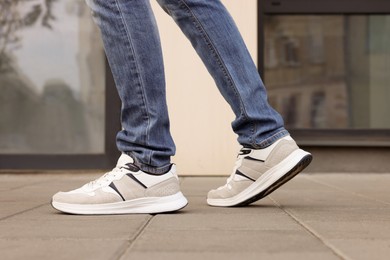 Man in jeans and sneakers walking on city street, closeup