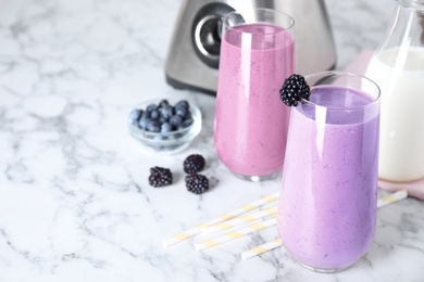 Tasty milk shakes and berries on white marble table