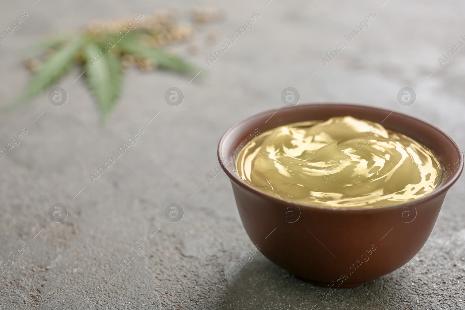 Photo of Bowl with hemp lotion and space for text on grey background