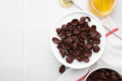 Photo of Breakfast cereal. Chocolate corn flakes and milk in bowl on white tiled table, flat lay. Space for text