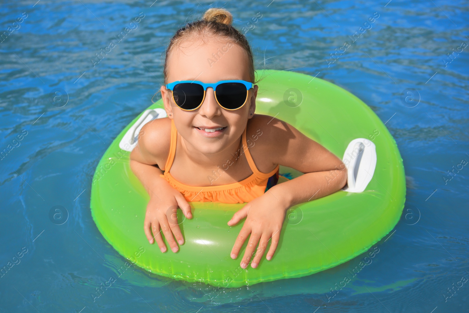 Photo of Happy little girl with sunglasses and inflatable ring in sea on sunny day. Beach holiday