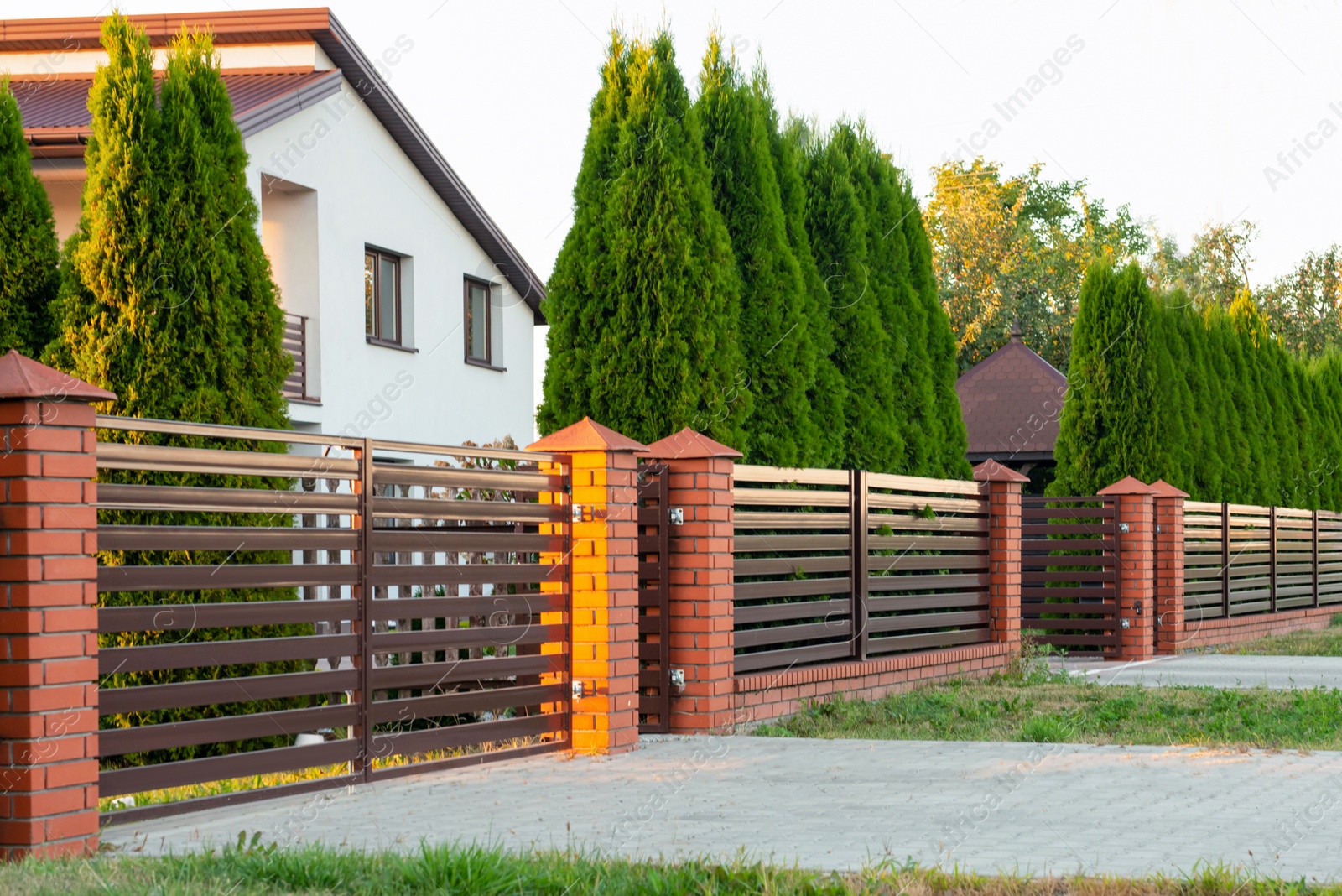 Photo of Beautiful brick fence with iron panels outdoors