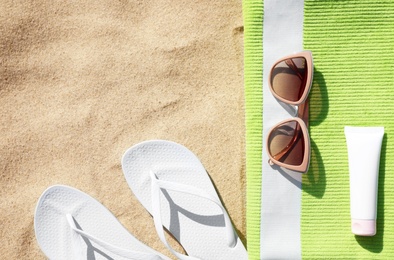 Flat lay composition with different beach accessories on sand. Space for text