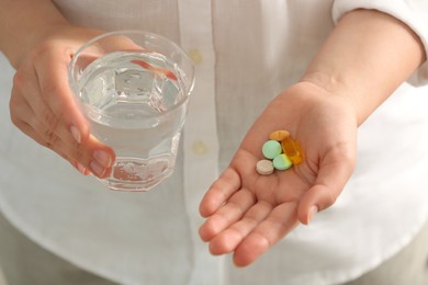 Photo of Young woman with glass of water and dietary supplement pills, closeup