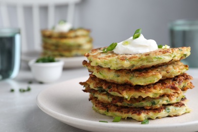 Photo of Delicious zucchini fritters served on light table indoors, closeup