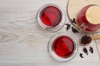 Photo of Cup of fresh hibiscus tea and dry flower leaves on wooden table, flat lay. Space for text